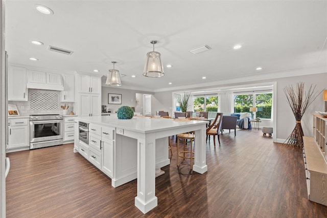 kitchen with dark wood-type flooring, white cabinets, decorative light fixtures, a kitchen island, and stainless steel appliances