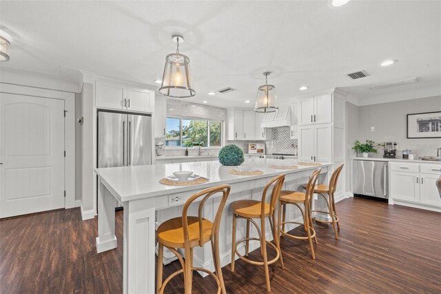 kitchen with white cabinets, dark hardwood / wood-style floors, stainless steel fridge, and pendant lighting