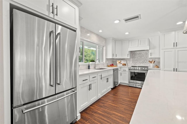 kitchen with sink, white cabinets, dark wood-type flooring, and appliances with stainless steel finishes