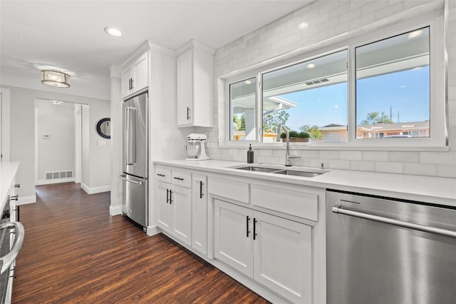 kitchen with appliances with stainless steel finishes, tasteful backsplash, sink, dark hardwood / wood-style floors, and white cabinetry