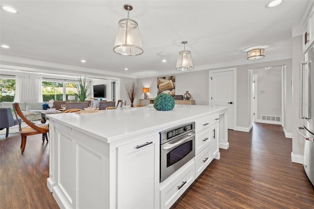 kitchen with a kitchen island with sink, oven, dark hardwood / wood-style floors, decorative light fixtures, and white cabinetry