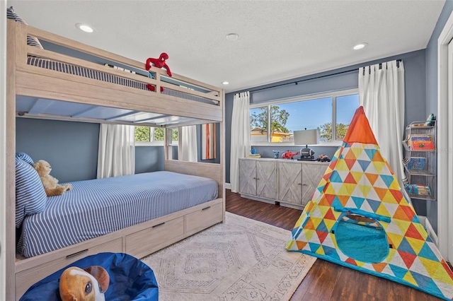 bedroom with multiple windows, wood-type flooring, and a textured ceiling