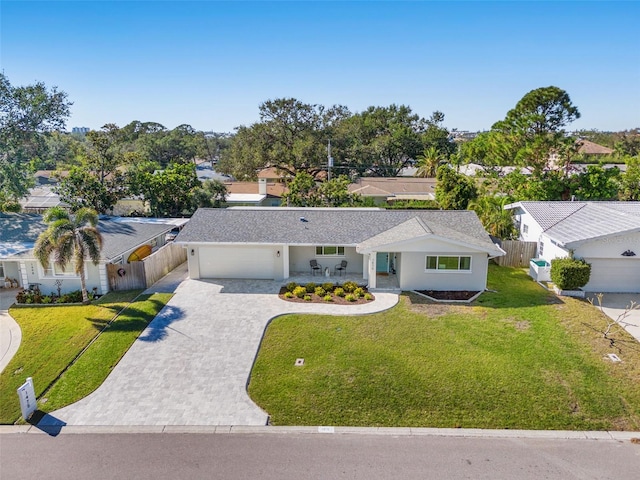 ranch-style home featuring decorative driveway, fence, and a front lawn