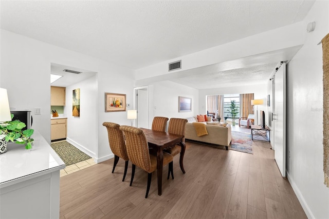 dining room featuring light hardwood / wood-style floors and a textured ceiling