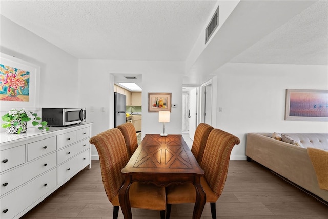 dining room with a textured ceiling, dark hardwood / wood-style flooring, and sink