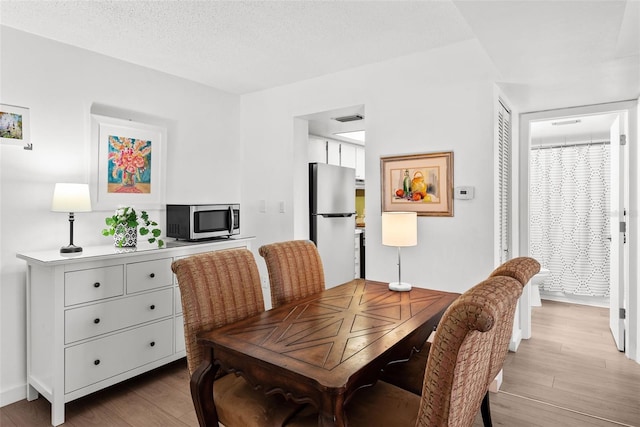 dining room with a textured ceiling and light hardwood / wood-style flooring