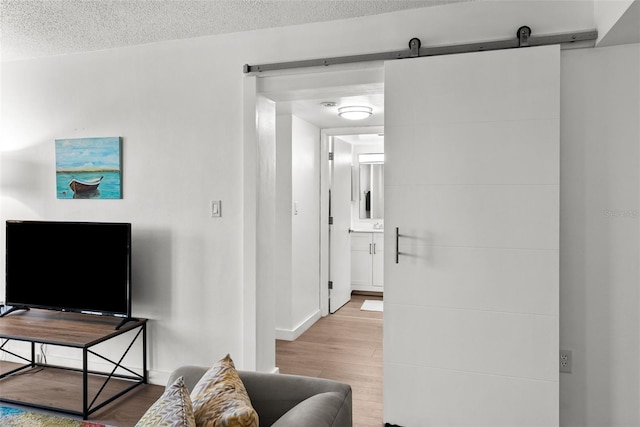 living room featuring light wood-type flooring, a textured ceiling, and a barn door