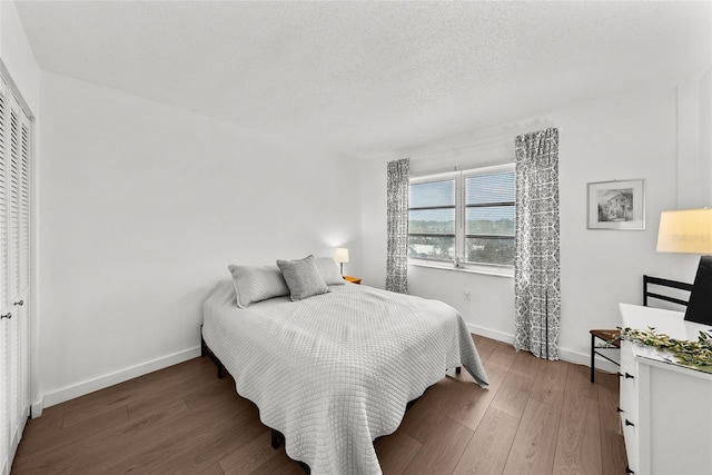 bedroom with a textured ceiling, a closet, and dark wood-type flooring