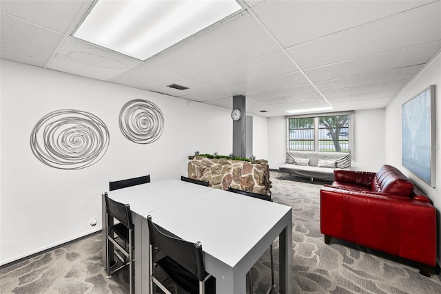 carpeted dining area with a paneled ceiling