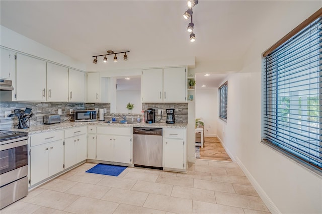 kitchen with tasteful backsplash, white cabinets, stainless steel appliances, and rail lighting