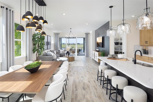 dining room with light hardwood / wood-style floors, an inviting chandelier, a wealth of natural light, and sink