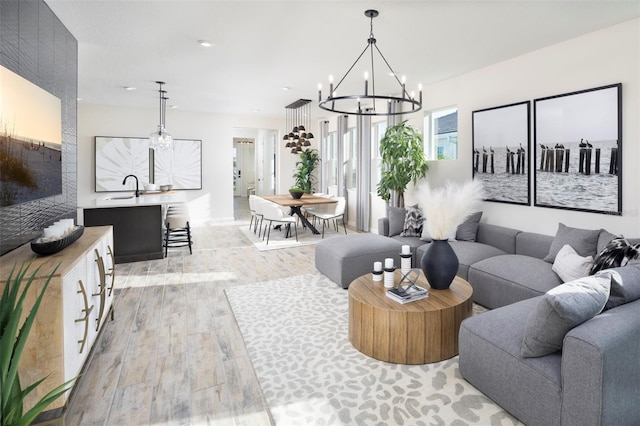 living room featuring a notable chandelier, sink, and light hardwood / wood-style flooring