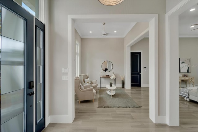 entrance foyer featuring light wood-type flooring, ceiling fan, and crown molding