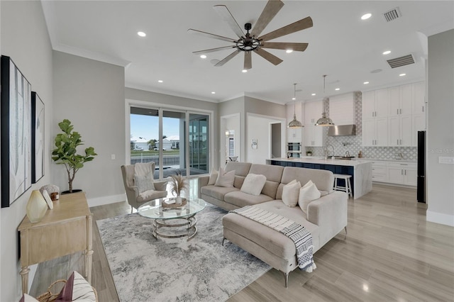 living room with ceiling fan, crown molding, and light wood-type flooring