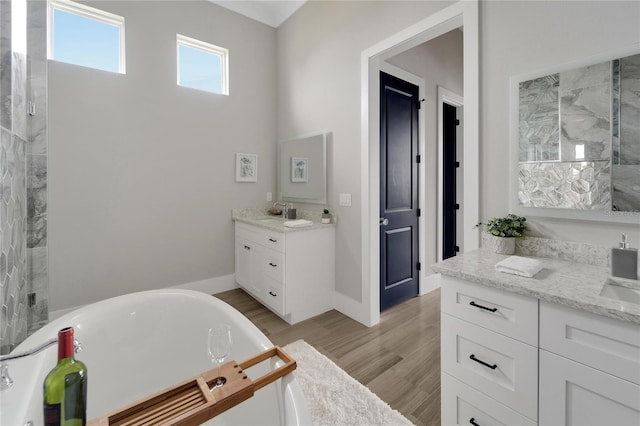 5713 Tybee Island Dr, Apollo Beach, FL 33572 - full bathroom featuring two vanities, a soaking tub, wood finished floors, and baseboards