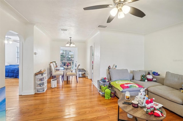 living room featuring ceiling fan with notable chandelier and light hardwood / wood-style floors