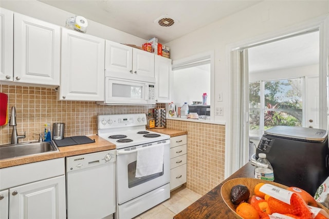 kitchen featuring white appliances, backsplash, white cabinets, sink, and light tile patterned flooring