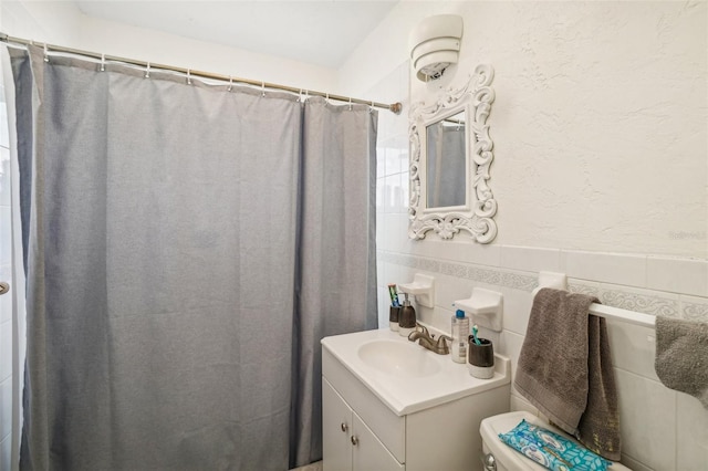 bathroom featuring vanity, toilet, tile walls, and walk in shower