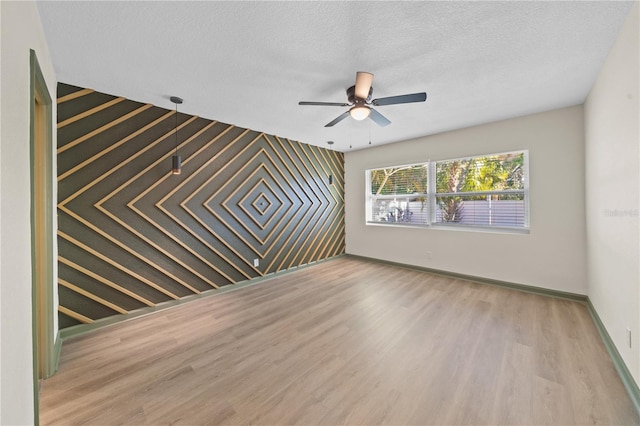 spare room featuring ceiling fan, light hardwood / wood-style floors, and a textured ceiling