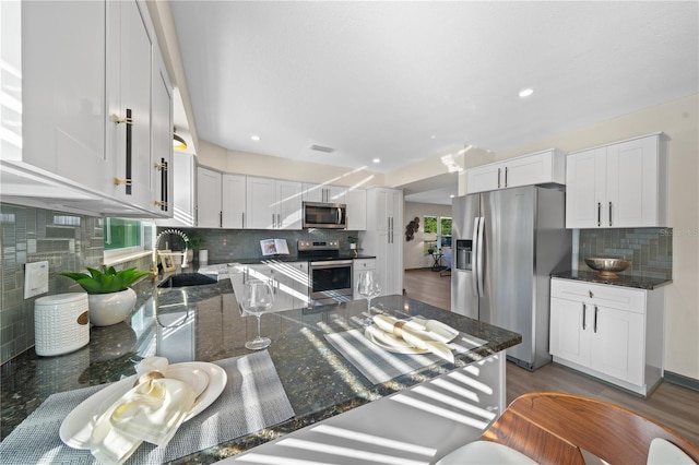 kitchen with dark stone countertops, white cabinetry, dark hardwood / wood-style flooring, and appliances with stainless steel finishes