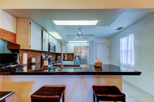 kitchen featuring kitchen peninsula, white cabinetry, a breakfast bar, and appliances with stainless steel finishes