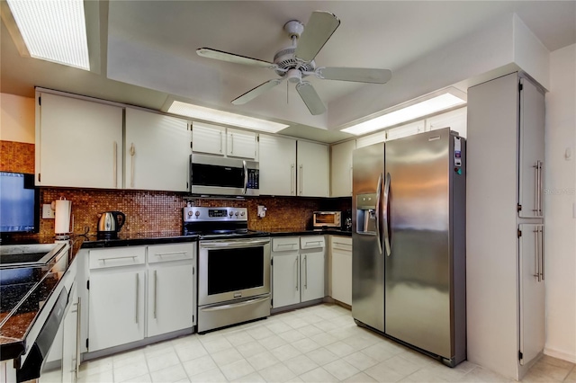 kitchen featuring decorative backsplash, appliances with stainless steel finishes, white cabinets, and ceiling fan