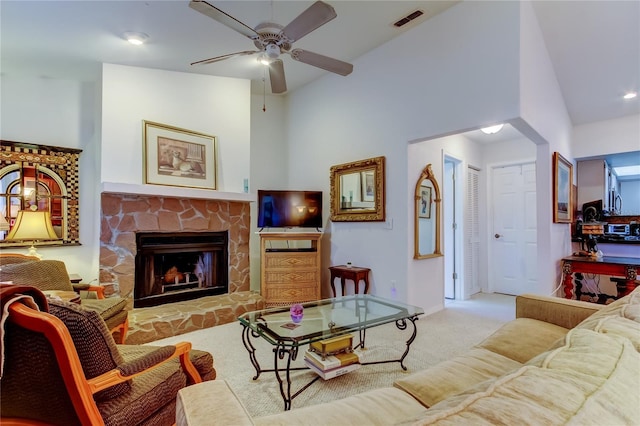 living room with light carpet, high vaulted ceiling, a stone fireplace, and ceiling fan