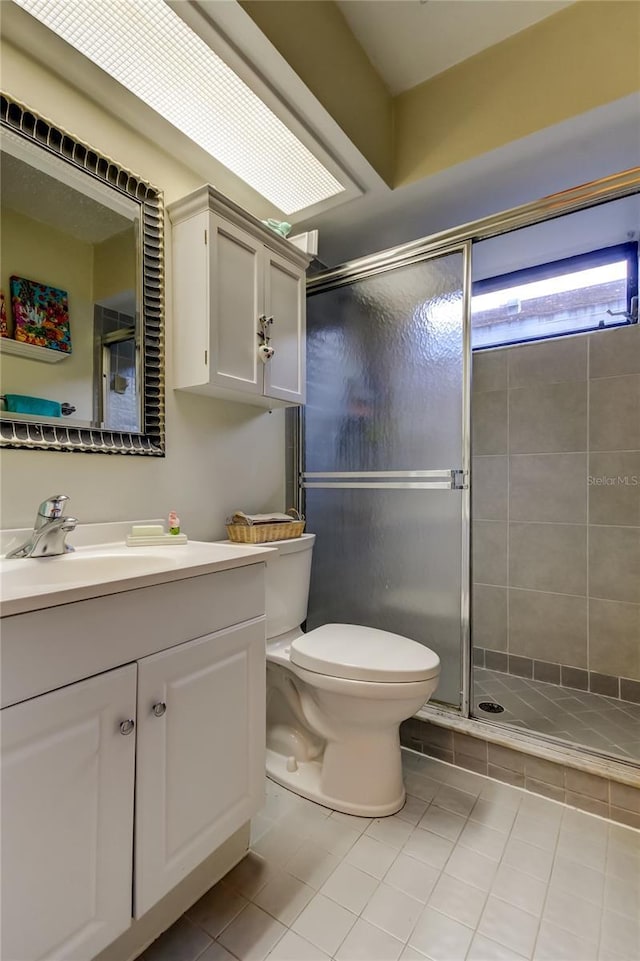 bathroom with tile patterned flooring, vanity, toilet, and a shower with shower door