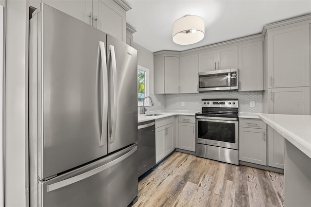 kitchen with gray cabinets, sink, light hardwood / wood-style floors, and appliances with stainless steel finishes