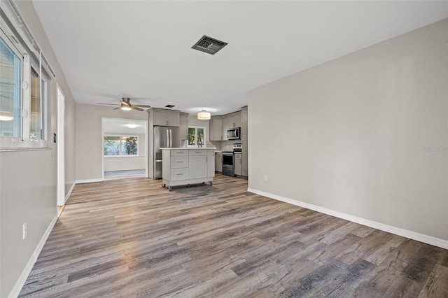 kitchen with a center island, ceiling fan, gray cabinets, light wood-type flooring, and stainless steel appliances