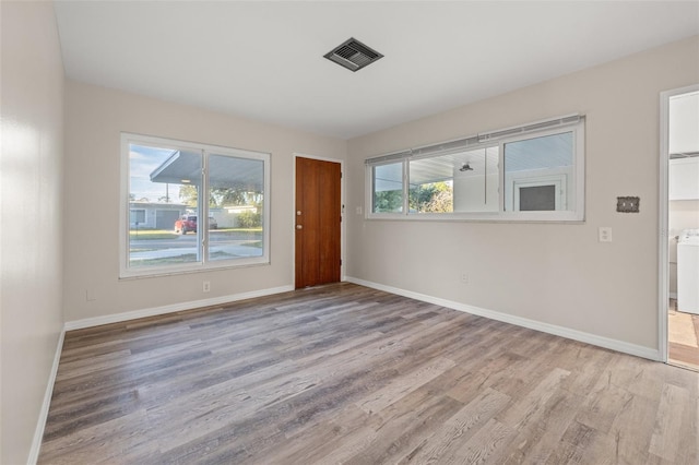 spare room featuring a healthy amount of sunlight, washer / dryer, and light hardwood / wood-style floors