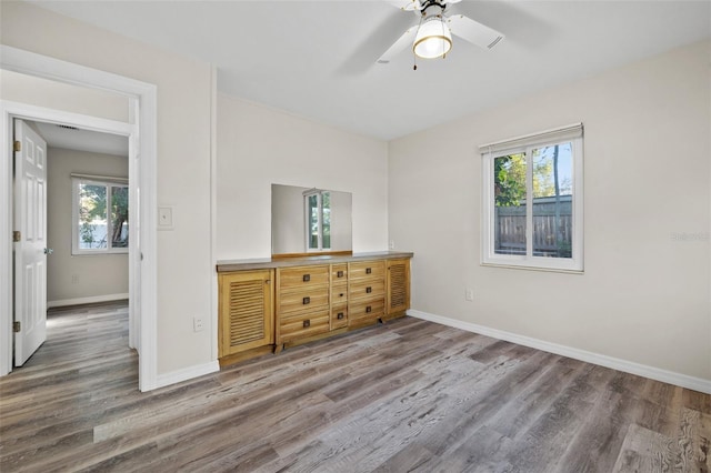 unfurnished bedroom featuring hardwood / wood-style flooring, ceiling fan, and multiple windows