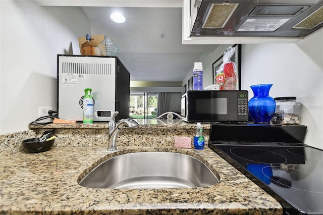 kitchen featuring stone counters, range, extractor fan, and sink