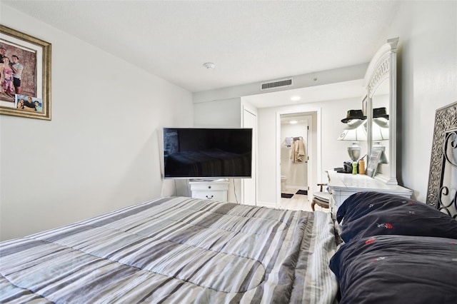 bedroom featuring a textured ceiling and connected bathroom