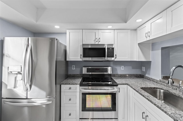 kitchen featuring stone counters, appliances with stainless steel finishes, white cabinetry, and sink