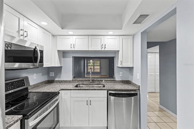 kitchen with dark stone counters, white cabinetry, sink, and stainless steel appliances