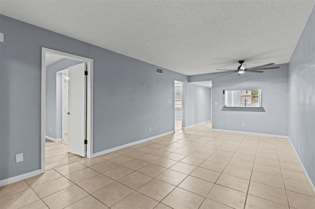 unfurnished room featuring ceiling fan, light tile patterned flooring, and a textured ceiling