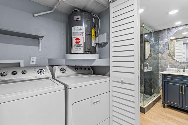 washroom with washer and dryer, light wood-type flooring, electric water heater, and sink