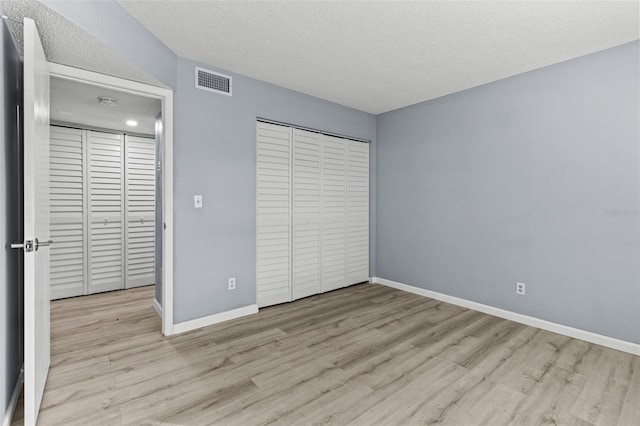 unfurnished bedroom featuring light wood-type flooring, a textured ceiling, and a closet