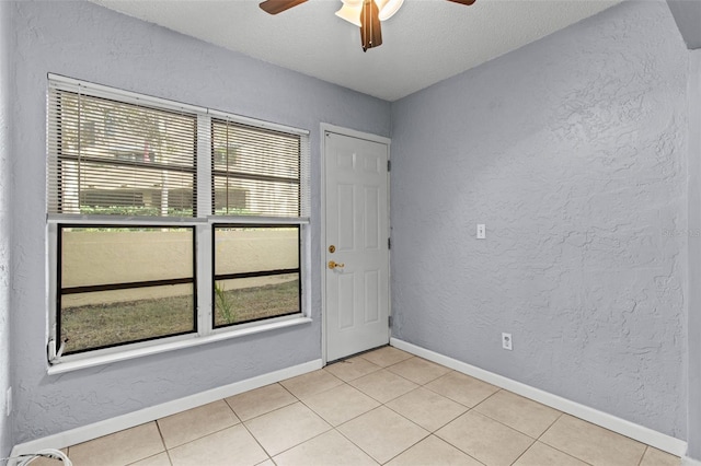 spare room featuring ceiling fan, light tile patterned floors, and a textured ceiling