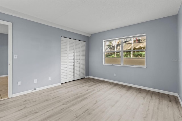 unfurnished bedroom featuring a closet, a textured ceiling, and light wood-type flooring