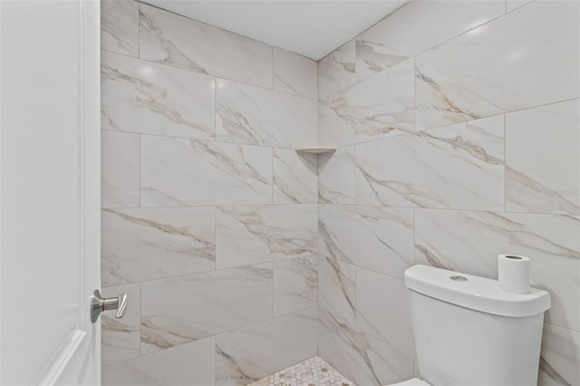 bathroom with a tile shower, tile walls, and toilet