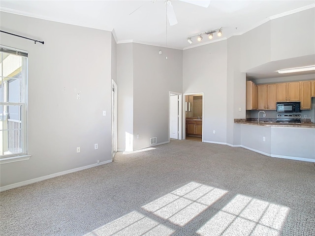 unfurnished living room featuring track lighting, ornamental molding, light colored carpet, ceiling fan, and sink