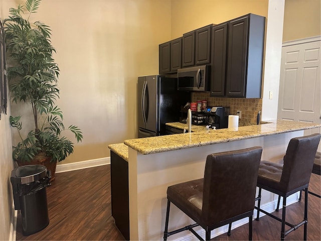 kitchen featuring a kitchen bar, kitchen peninsula, and appliances with stainless steel finishes