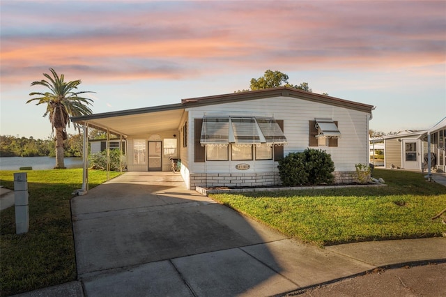 manufactured / mobile home featuring a carport and a yard