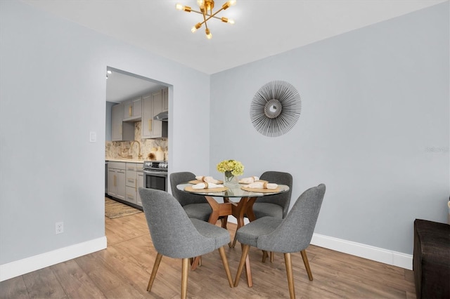 dining space featuring light hardwood / wood-style flooring, a chandelier, and sink