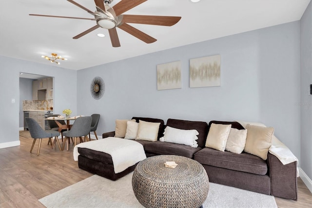 living room featuring ceiling fan, sink, and light hardwood / wood-style flooring