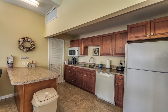 kitchen featuring kitchen peninsula, white appliances, sink, tile patterned flooring, and a breakfast bar area