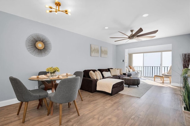 living area with recessed lighting, baseboards, wood finished floors, and ceiling fan with notable chandelier