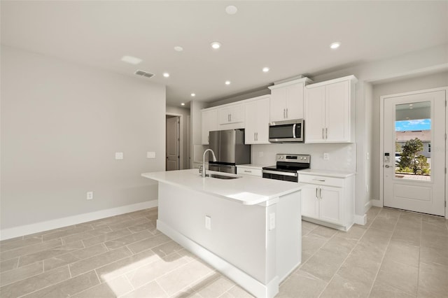 kitchen featuring sink, a center island with sink, light tile patterned floors, appliances with stainless steel finishes, and white cabinets